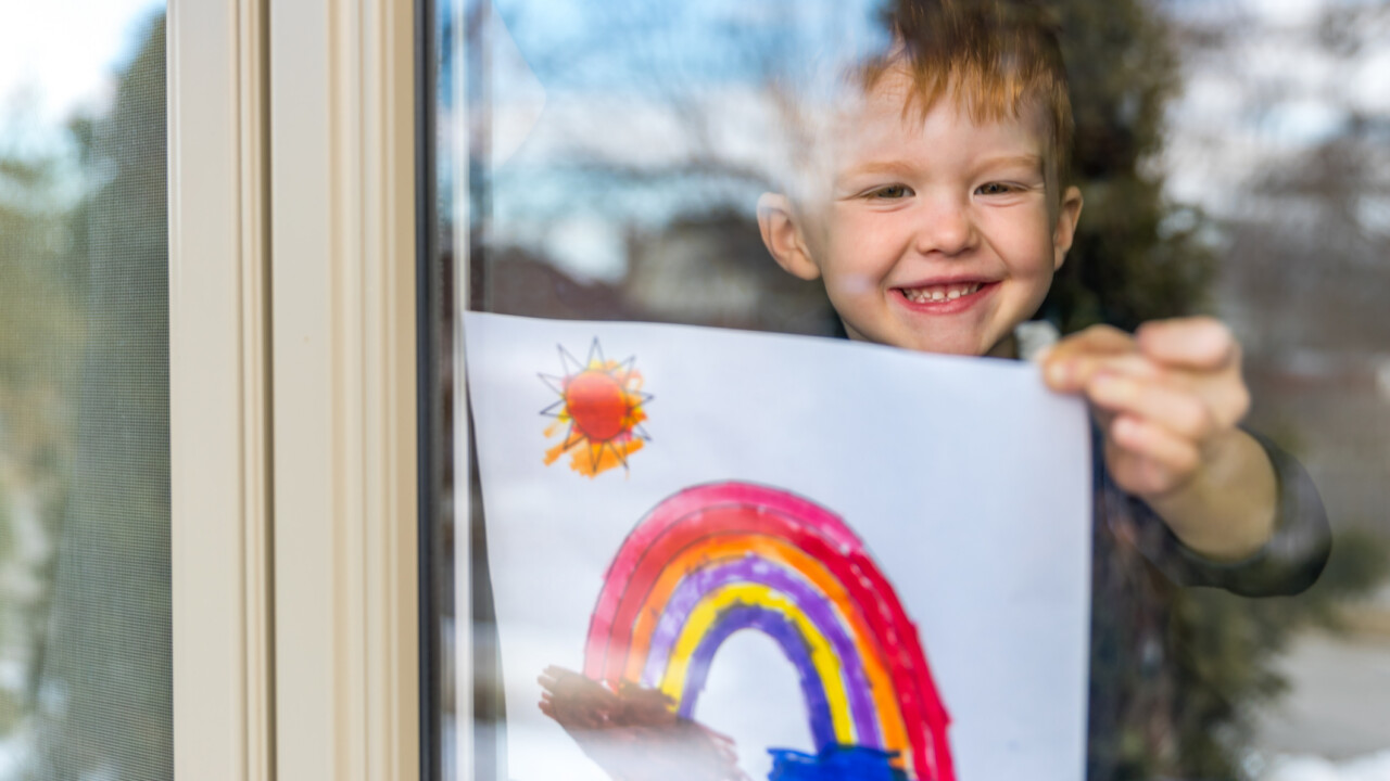 little boy holding up his painting to show it off.