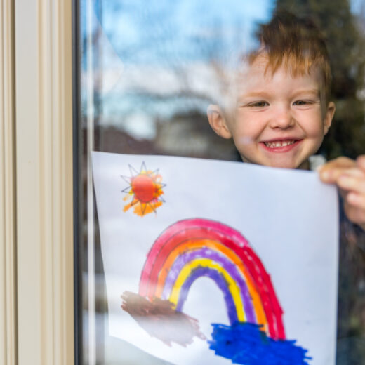 little boy holding up his painting to show it off.