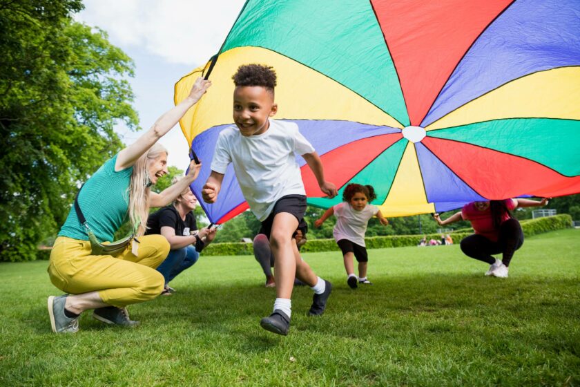 Little boy running under parachute.